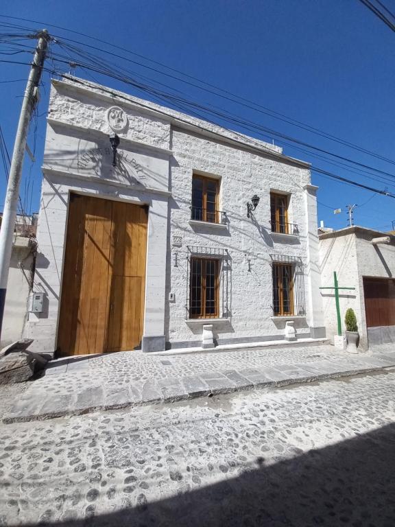 a white brick building with windows on a street at Quinta Alpaca - Departamento 1er piso in Arequipa