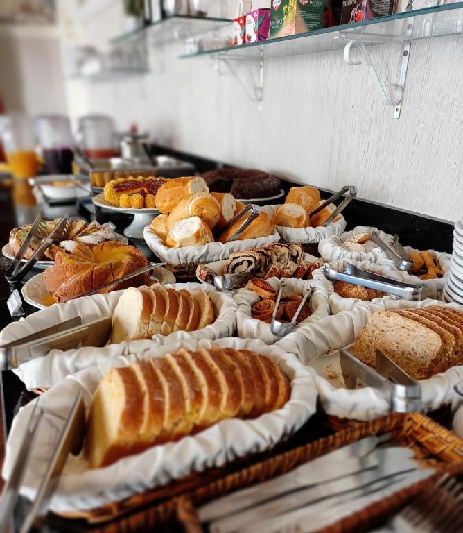 a buffet with many different types of bread and pastries at Hotel Cabana Jardim de Flores in Gramado