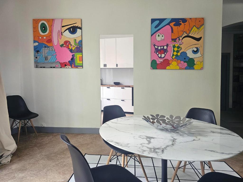 a table and chairs in a room with paintings at L&#39;Idrac, Appartements en Hyper centre in Toulouse