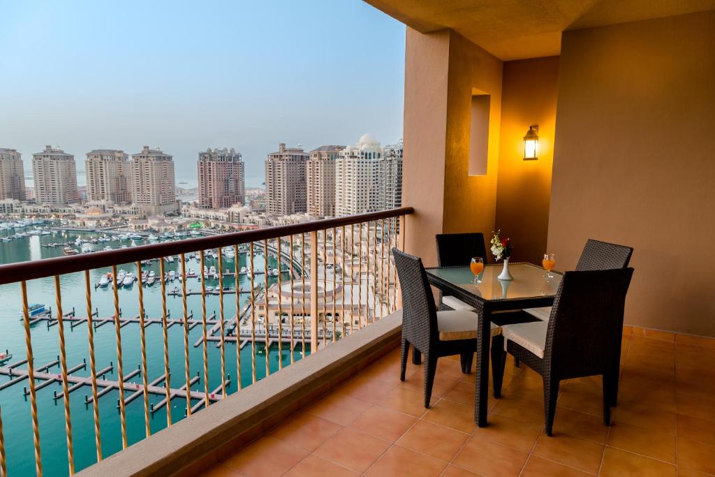 a balcony with a table and chairs and a view of a harbor at Sedra Arjaan by Rotana in Doha