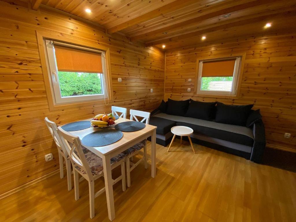 a room with a table and a couch in a cabin at Domki u Barta in Trzęsacz