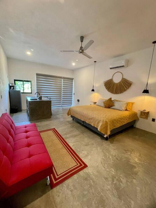 a bedroom with a bed and a red couch at océano estudio 2 in Sayulita