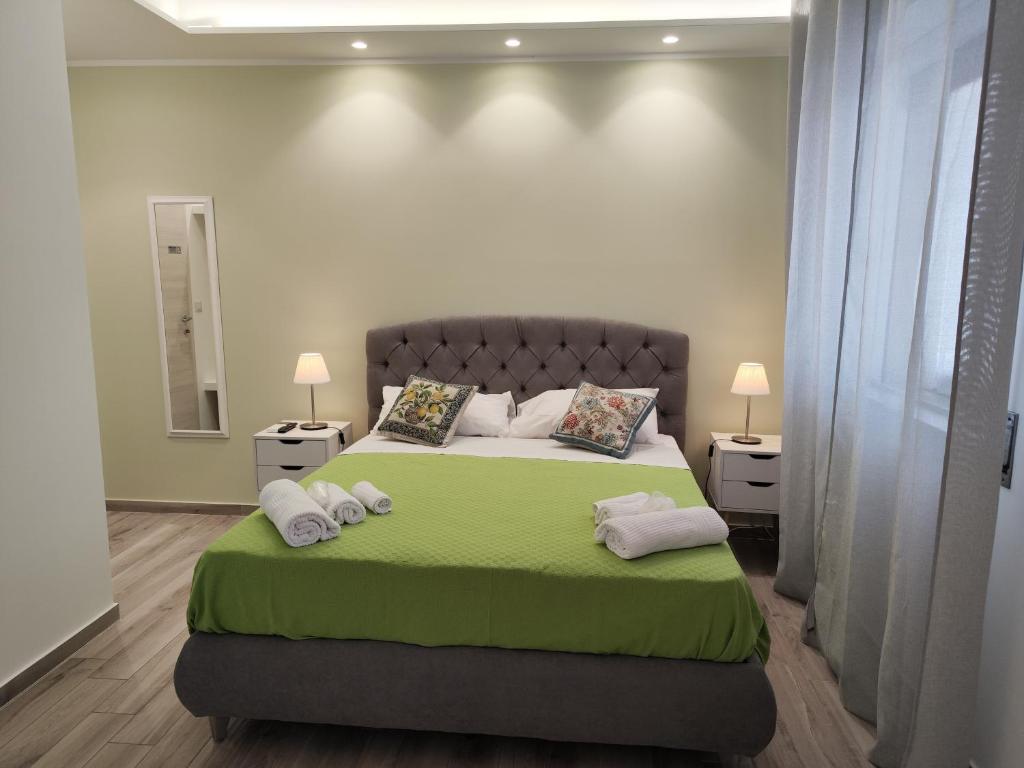 a bedroom with a large bed with green sheets and pillows at B&B CESARE'S Guests in Acitrezza