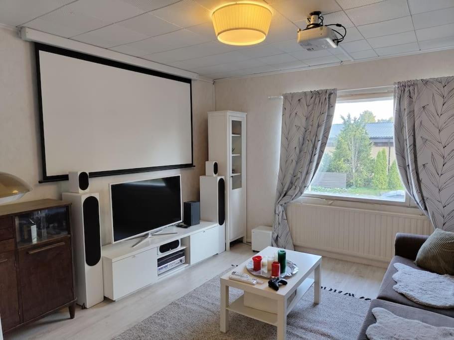 een woonkamer met een flatscreen-tv en een bank bij Omakotitalo rauhallisella alueella in Rauma