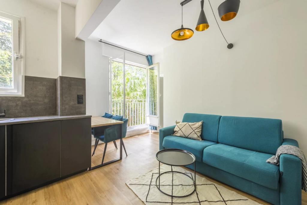 sala de estar con sofá azul y mesa en Appartement 2 pièces 4 couchages tout confort, en Neuilly-sur-Seine