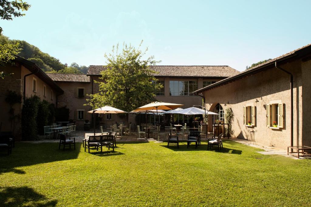 a yard with tables and chairs and umbrellas at Locanda Cà dei Santi in Induno Olona