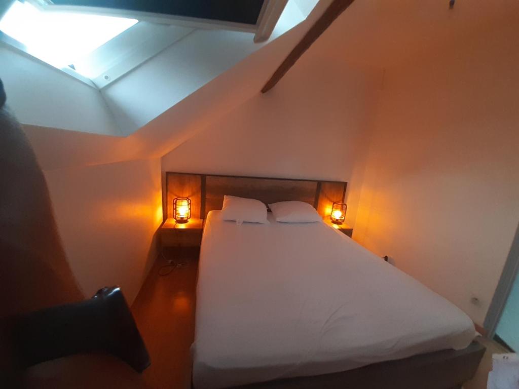 a bedroom with a bed with white sheets and two lights at T2 4p ste Savine proche centre Troyes in Sainte-Savine