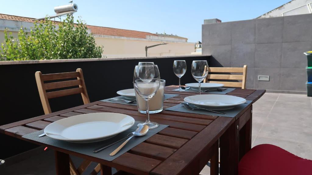 a wooden table with plates and wine glasses on a balcony at SottoMayor Best Residence in Figueira da Foz