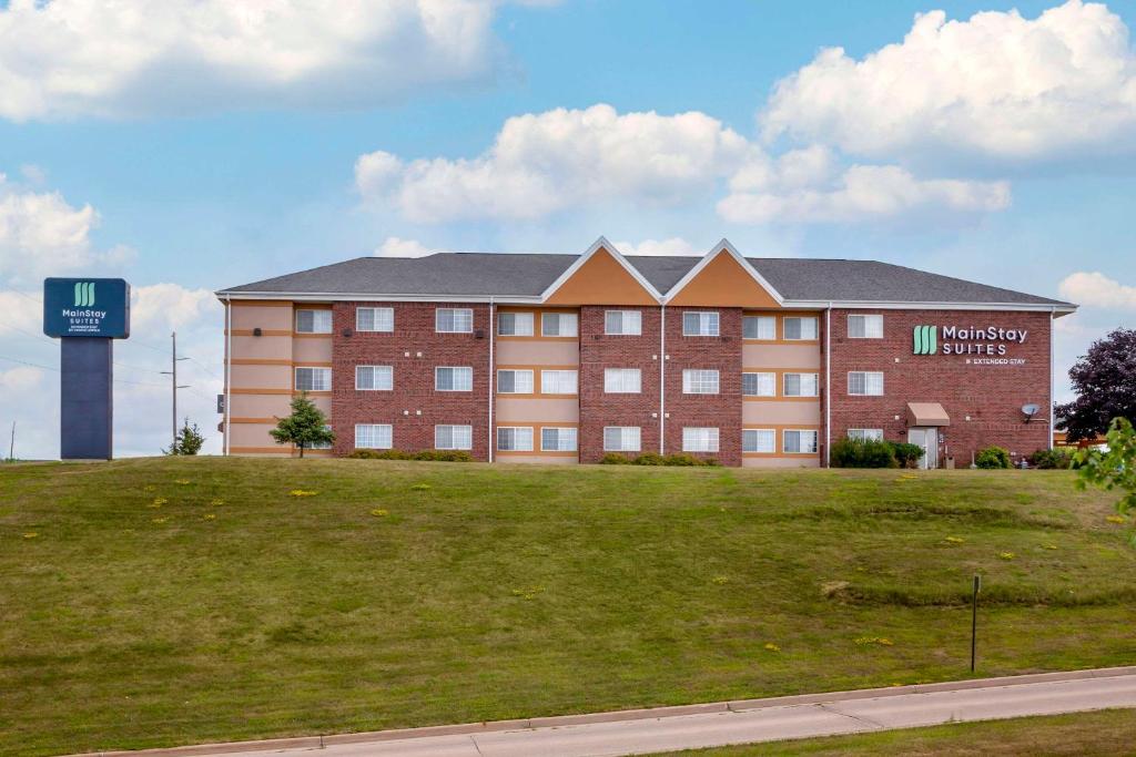 a large brick building with a grass field in front of it at MainStay Suites Dubuque at Hwy 20 in Dubuque