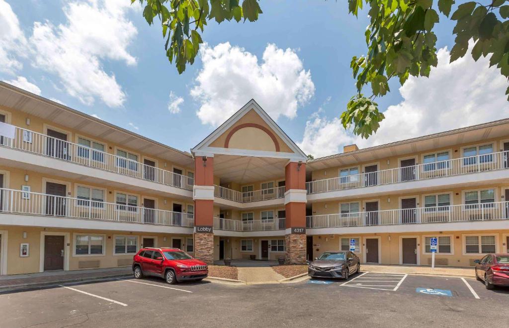 um grande edifício com dois carros estacionados num parque de estacionamento em Extended Stay America Suites - Greensboro - Wendover Ave - Big Tree Way em Greensboro