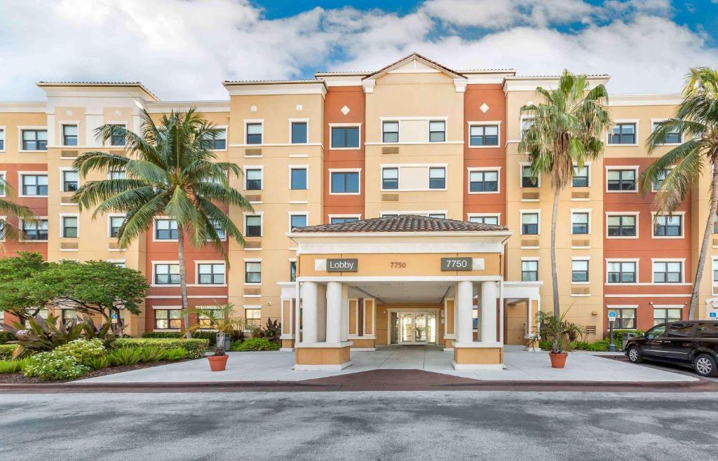 un grand bâtiment avec des palmiers devant lui dans l'établissement Extended Stay America Premier Suites - Miami - Airport - Doral - 25th Street, à Miami