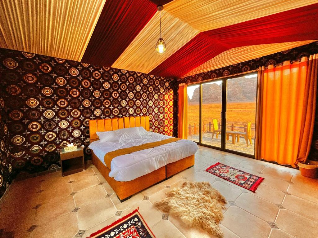 a bedroom with a bed and a large window at Magic Bedouin Star in Wadi Rum