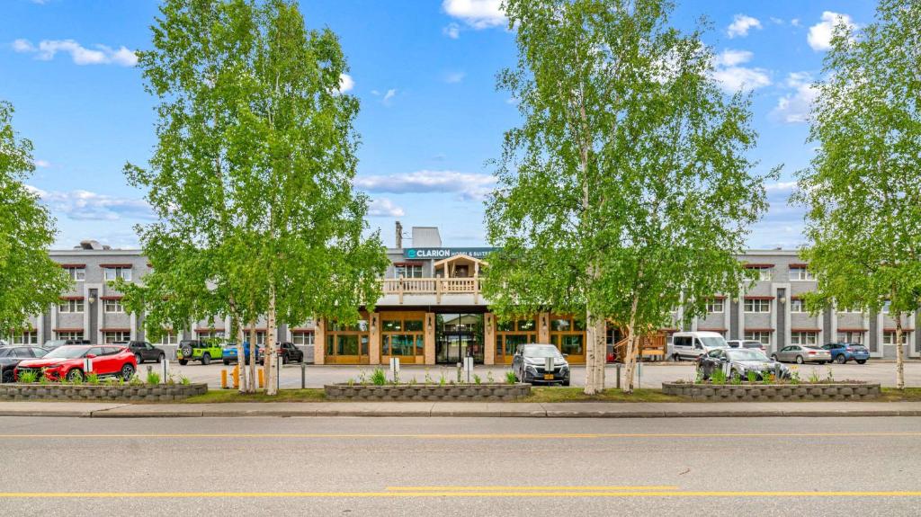 a building with trees in front of a parking lot at Clarion Hotel & Suites Fairbanks near Ft Wainwright in Fairbanks