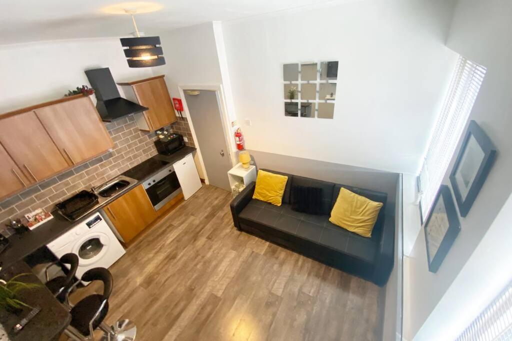 uma sala de estar com um sofá preto e almofadas amarelas em The Anchor -South Shields em South Shields