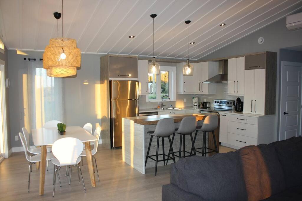a kitchen and living room with a table and chairs at Luxueux chalet sur la plage - Baie des Chaleurs in Caraquet