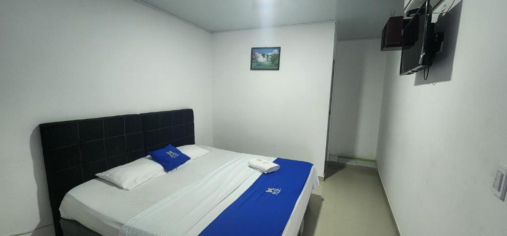 Habitación pequeña con cama con sábanas azules y blancas. en Hotel Noz INN, en Villavicencio
