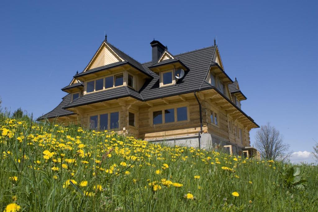 a house on a hill with a field of flowers at Nowe Miejsce Brzegi in Brzegi
