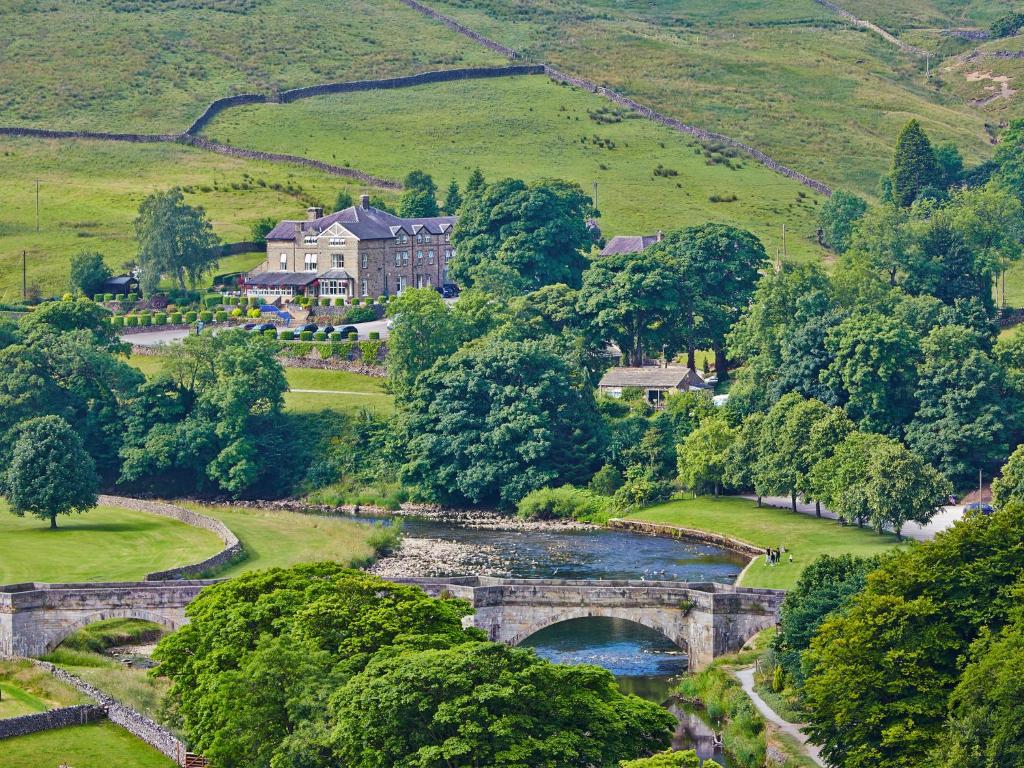 an aerial view of a house and a bridge over a river at The Devonshire Fell Hotel in Burnsall
