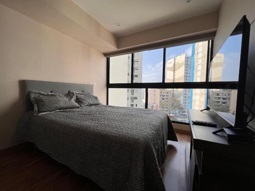 1 dormitorio con cama y escritorio con ventana en Apartament Social Tree 907 en Lima