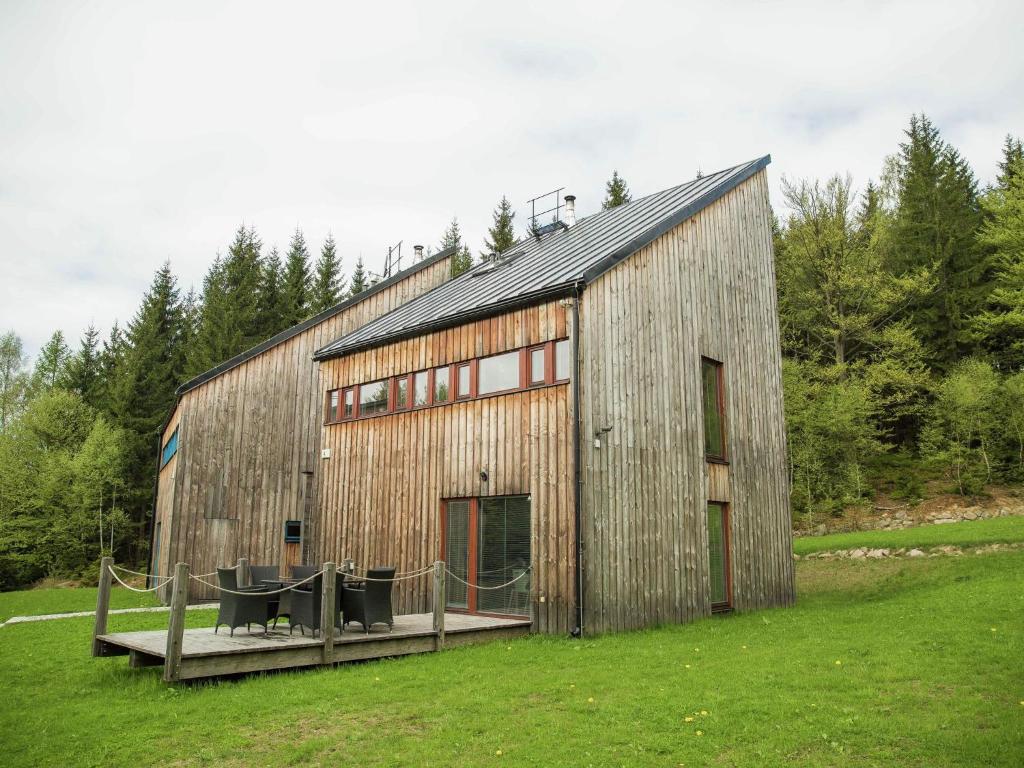 a large wooden barn with a table in a field at Spacious chalet in residential area, modern, luxury interior, large terrace in Harrachov