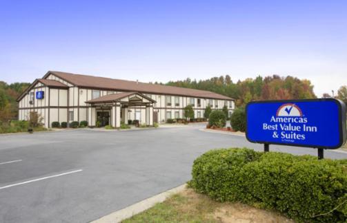 un gran edificio con una señal azul delante de él en Americas Best Value Inn and Suites Albemarle, en Albemarle