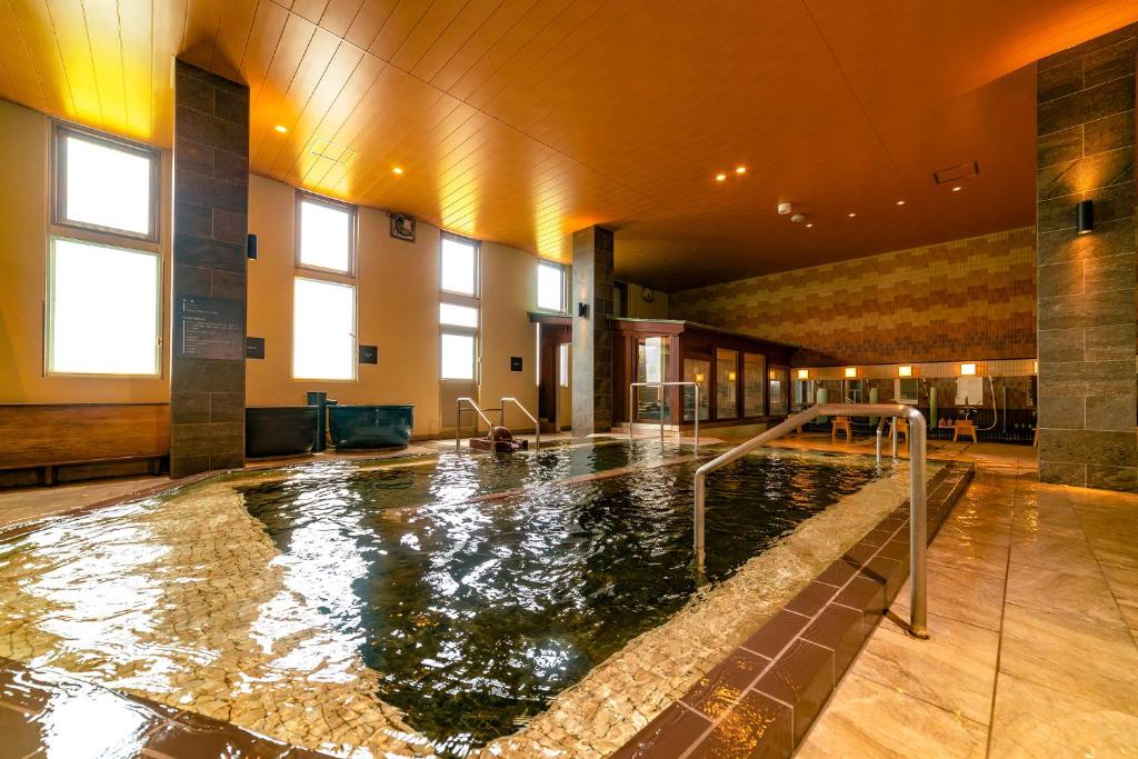 une grande piscine intérieure dans un bâtiment dans l'établissement Ooedo Onsen Monogatari Premium Kinosaki, à Toyooka