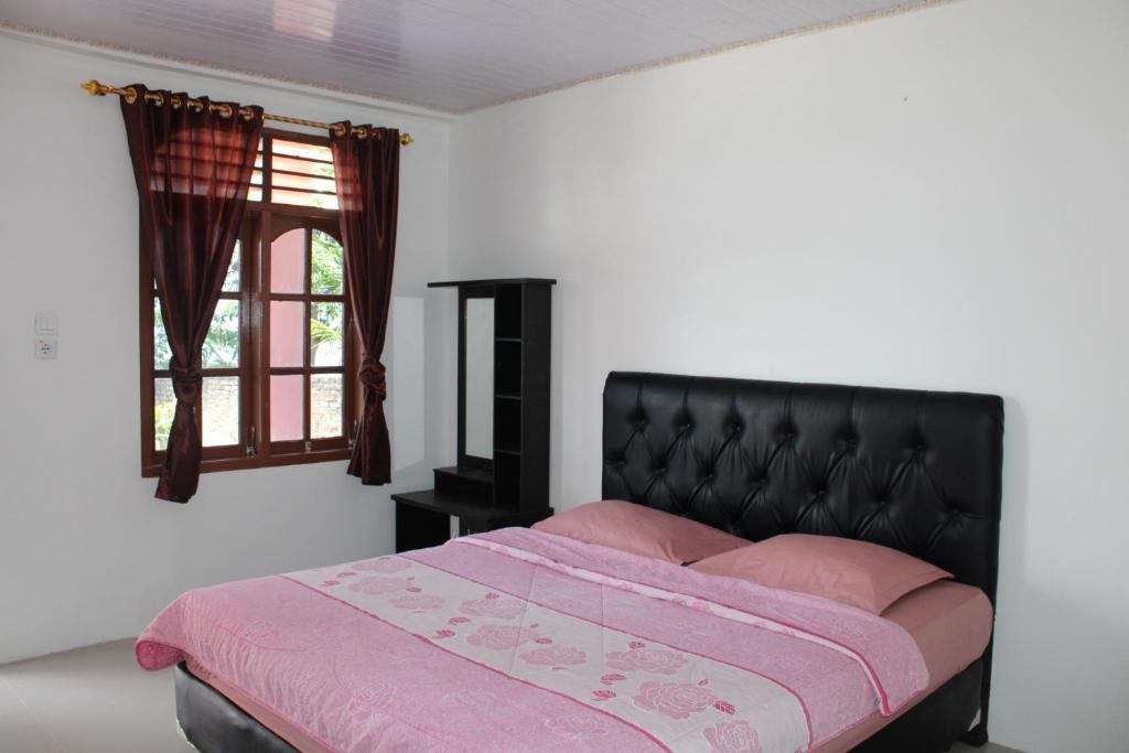 um quarto com uma cama com lençóis cor-de-rosa e uma janela em Hotel Barbara em Tuktuk Siadong