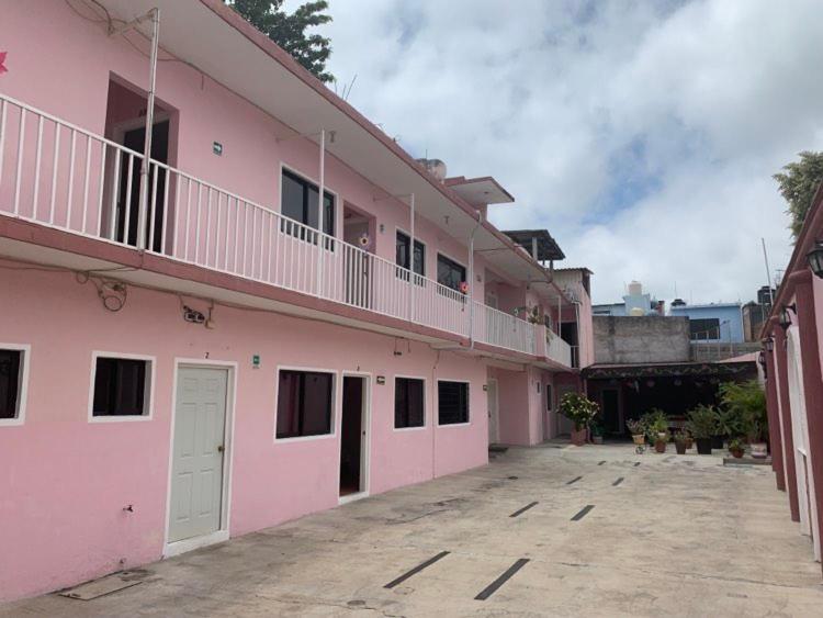 a pink building with a balcony and a parking lot at Hotel Jacaranda in Tuxtla Gutiérrez