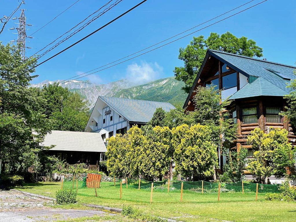 a house with a fence in front of it at Hakuba Pension & Log Hotel Meteor in Hakuba