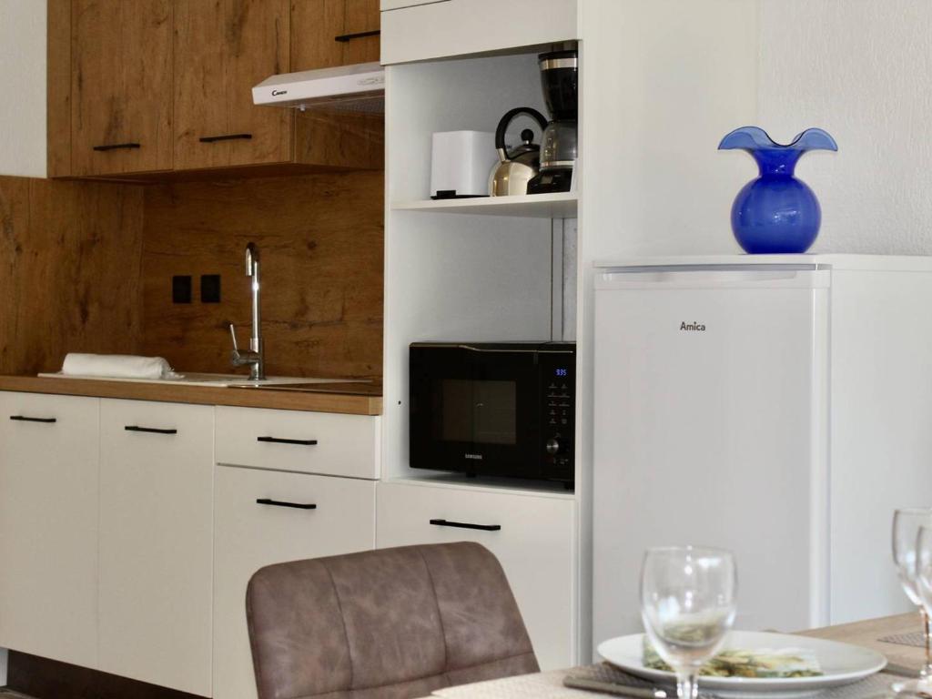 une cuisine avec des placards blancs et un vase bleu sur une table dans l'établissement Appartement RDC à Villeneuve-Loubet - 2 Pièces, 45m², 4 Couchages, Plage à 100m - FR-1-252A-113, à Villeneuve-Loubet