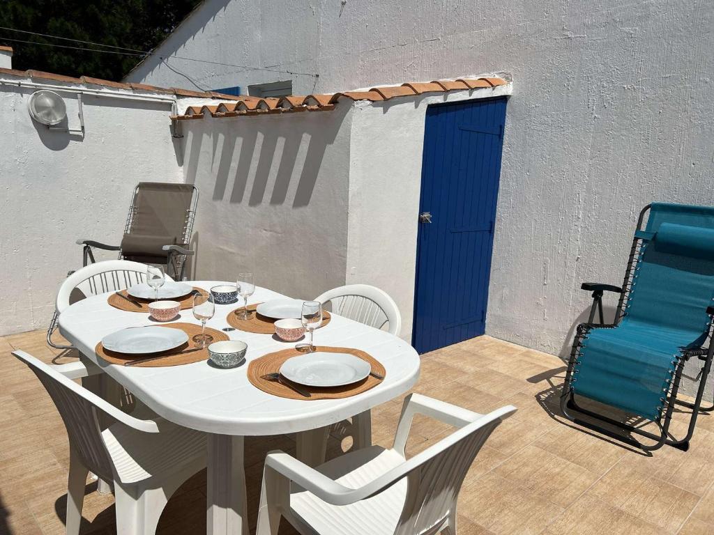 une table blanche et des chaises sur une terrasse dans l'établissement Maison cosy proche mer avec piscine chauffée, courts de tennis et patio - Bretignolles-sur-Mer - FR-1-224A-65, à Bretignolles-sur-Mer