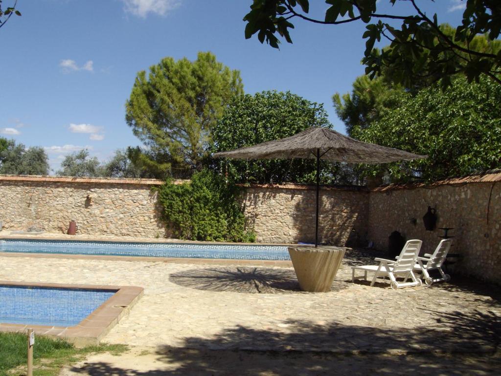 una sombrilla y sillas junto a la piscina en Set of rural houses in the center of Andalucia, en Humilladero