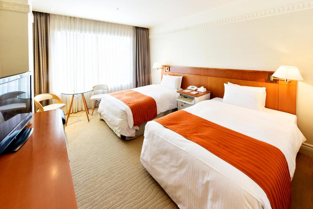 長崎市にあるTHE GLOBAL VIEW 長崎のベッド2台とテーブルが備わるホテルルームです。