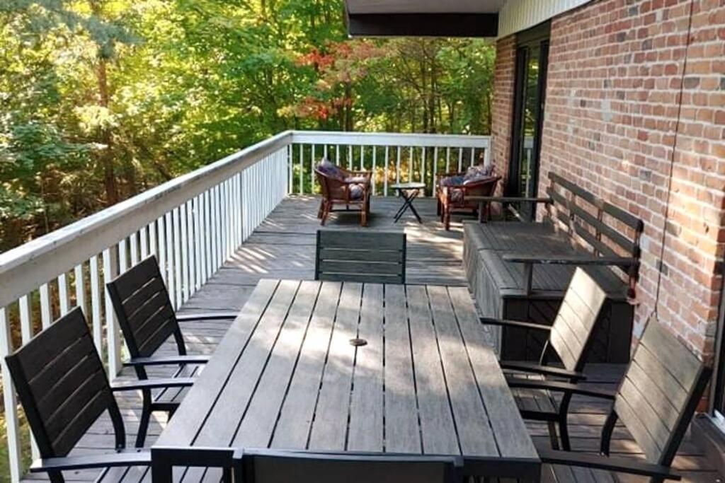 a wooden deck with chairs and tables on a house at Cozy Chalet in Sainte-Adèle