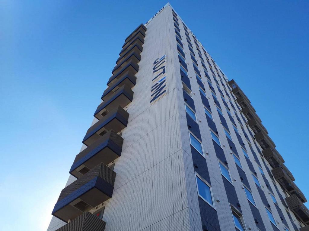 a tall building with a clock on the side of it at Just Inn Premium Toyohashi Station in Toyohashi