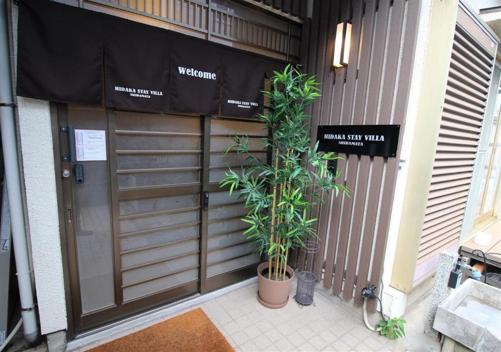 eine Garagentür mit zwei Pflanzen davor in der Unterkunft HIDAKA STAY VILLA 柴又 in Tokio