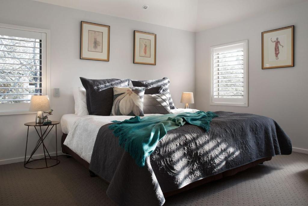 a bedroom with a bed and two windows at Courthouse Orchid Villa 6 in Daylesford