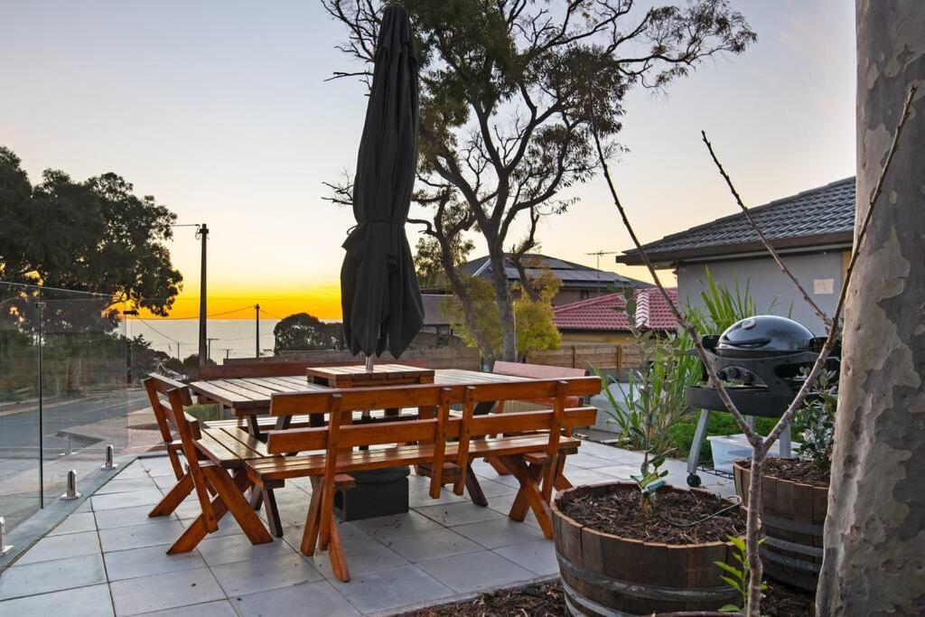 una mesa de picnic de madera con una sombrilla en el patio en Ocean Views Apartment 2 min walk to train & ocean, en Halletts Cove