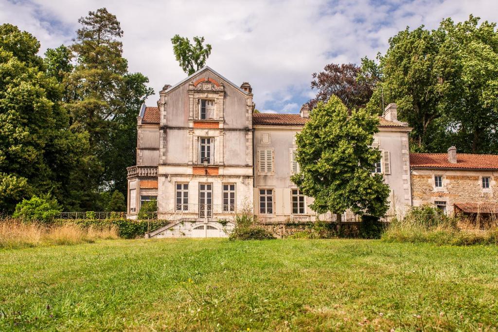 an old mansion with a large grass field at Le Domaine de Langlardie in Soudat