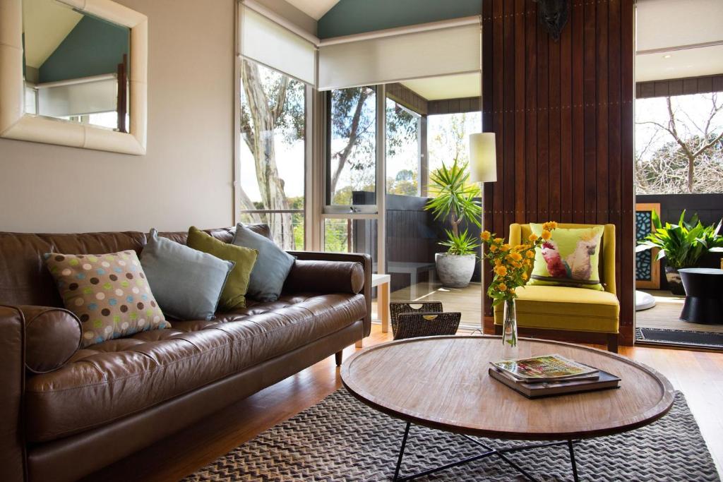 a living room with a leather couch and a table at Daylesford Spa Villa 6 in Daylesford