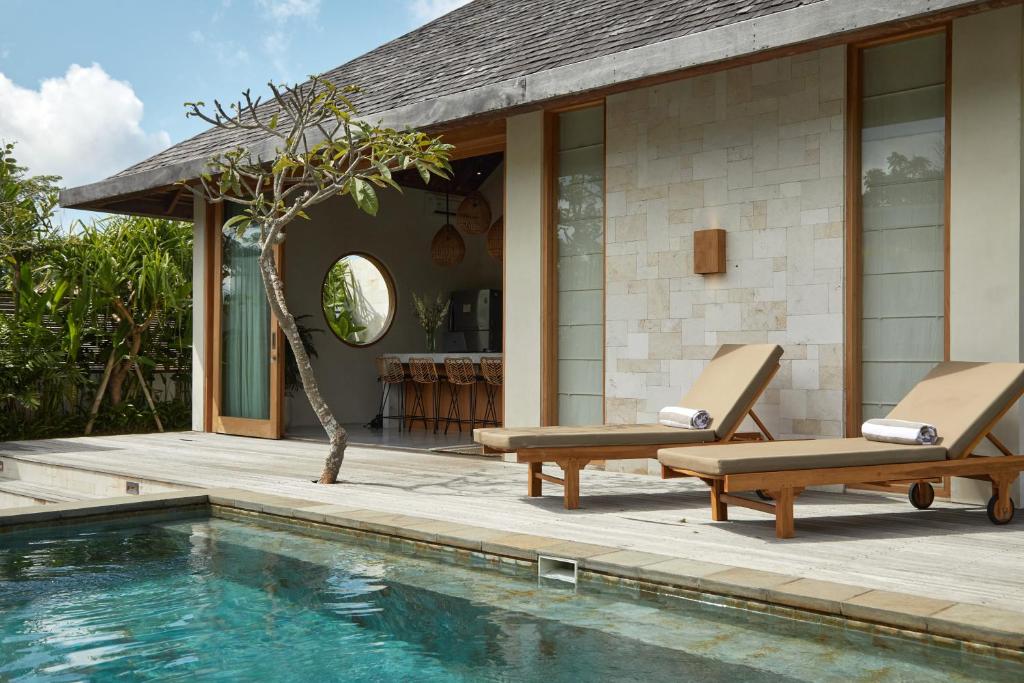 ウルワツにあるMona Boutique Villas & Spaのラウンジチェア2脚付きのスイミングプールが隣接しています。