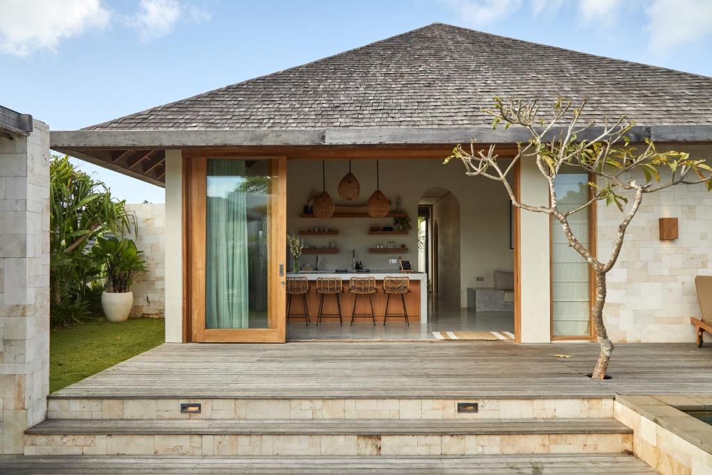 a house with a wooden porch with a kitchen at Villa Cerah in Uluwatu