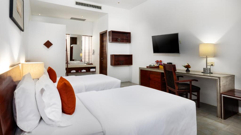 a hotel room with two beds and a desk at Lynnaya Urban River Resort in Siem Reap