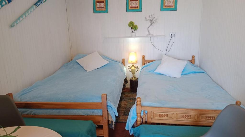 a bedroom with two beds and a table and a lamp at Cabaña y Hospedaje Rural La Familia in Dalcahue