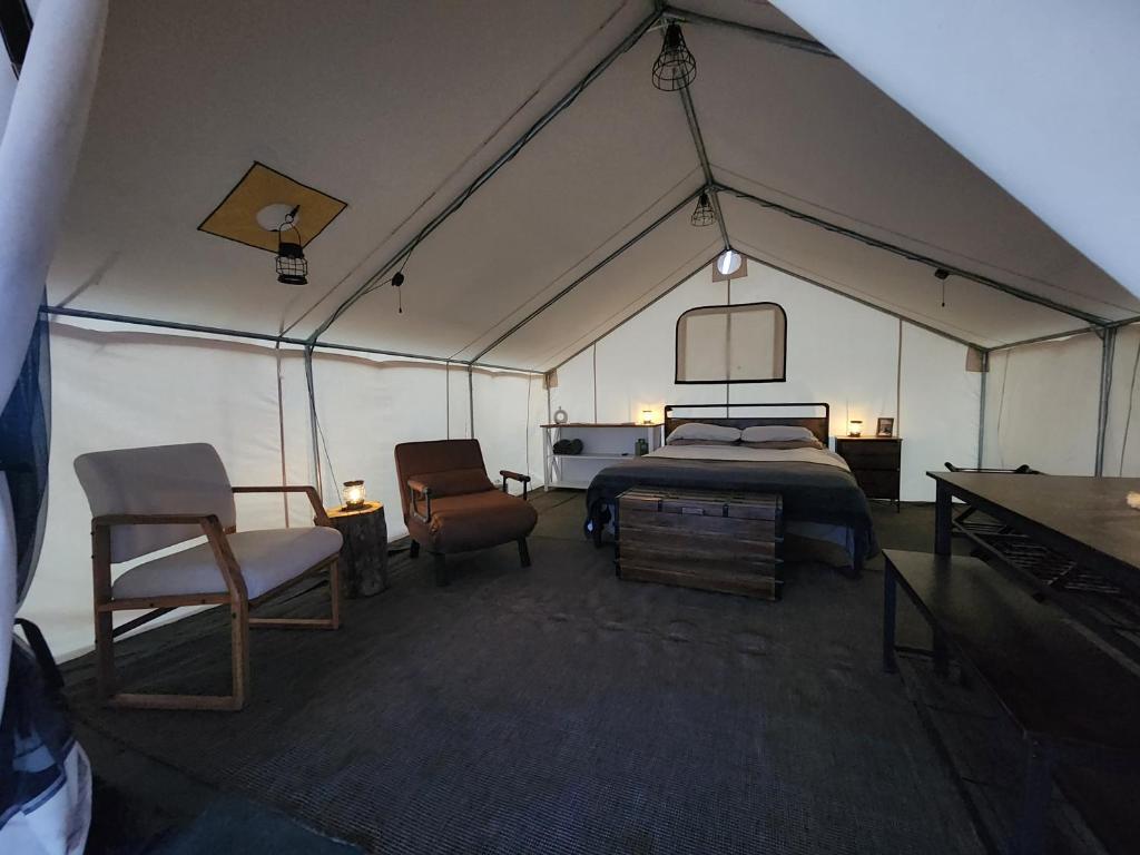 1 dormitorio en una tienda de campaña con 1 cama y sillas en Prairie Falcon, en Valle