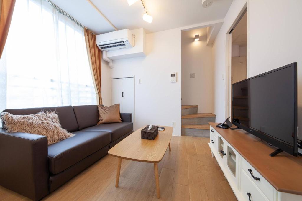 een woonkamer met een bank en een flatscreen-tv bij LEGALAND Gakushuin Shita in Tokyo