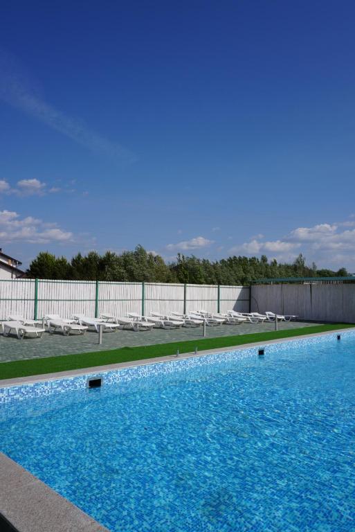 une grande piscine avec des chaises et une clôture dans l'établissement Гостевой дом ЧИСТЫЕ ПРУДЫ, à Koshi