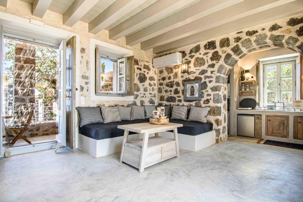 a living room with a couch in a stone wall at Pavlaina Complex of Traditional Residences in Nisyros. Enjoy the garden and the Sea View in Emporeiós