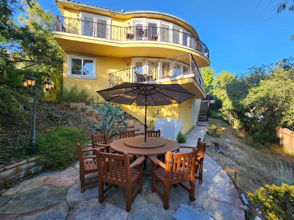 Hollywood Hills Hideout في لوس أنجلوس: طاولة مع كراسي ومظلة أمام المنزل