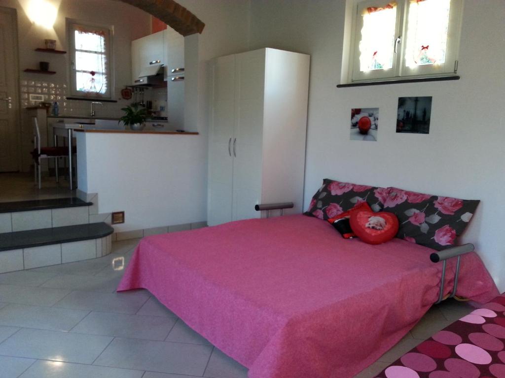 a bedroom with a pink bed and a kitchen at Il Giglio Rosso in Borgo a Buggiano